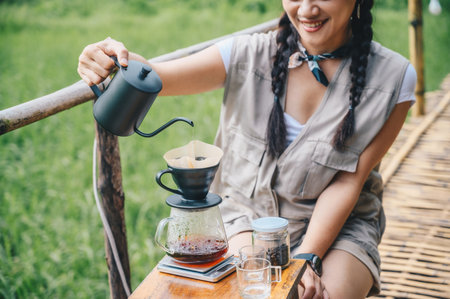 Tourist woman pouring hot water onto ground coffee beans with paper filter to make a drip coffee. Conceptual of how to making drip coffee by herself.の写真素材