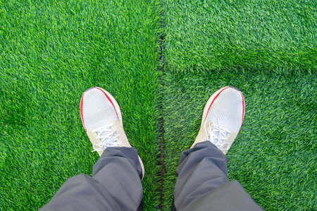 Cropped shot view of someone standing on green artificial turf in garden. Artificial grass are made by polyethylene or nylon, convenient and it does not require much maintenance.の写真素材