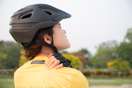 Asian female cyclist having neck pain from riding a bike long time. Poor posture is a major contributor to neck pain whilst cycling.の写真素材