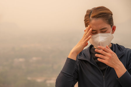 Asian woman having headache becaused of by Bad air pollution (PM2.5). PM2.5 levels meaning the air quality posed a health hazard.の写真素材