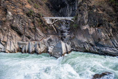 An old bridge opposite the landscape of Tiger Leaping Gorge in Yunnan province of China. Scenic spot where a tiger is said to have leaped across the river, thus giving the gorge itの写真素材