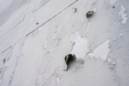 Peeling paint on gray concrete wall. Peeling, cracking, or blistering paint occurs when there is a loss of adhesion between the paint and the surface it's placed on.の写真素材