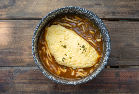 High angle view of Kare Udon topping with creamy omelet served on wooden table. Udon is a thick, white, ribbon-like noodle popular in Japanese cuisine.の写真素材