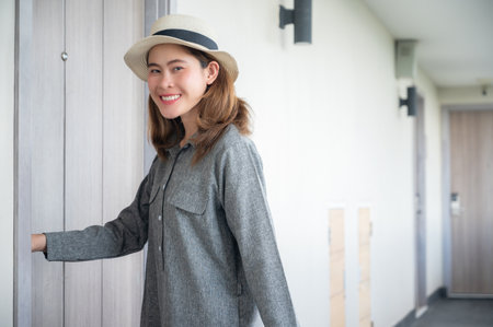 Happiness Asian tourist woman standing in front of hotel room. Conceptual shot of woman vacation and lifestyle.の写真素材