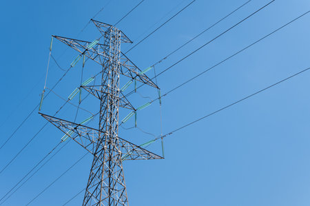 A transmission tower against blue sky. Transmission towers (electrical pylons) carry large amounts of high-voltage current over long distances.の写真素材