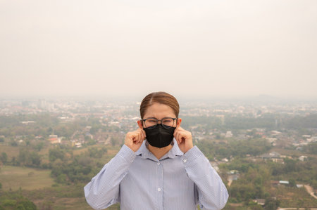 Asian businesswoman wearing N95 mask for protect Bad air pollution (PM2.5). PM2.5 levels meaning the air quality posed a health hazard.の写真素材