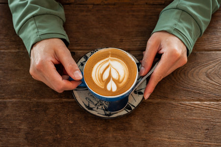 Woman hands holding a cup of hot Cappuccino coffee before drinking. The taste of cappuccinos can be...