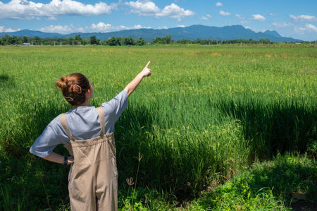 Rear view of woman pointing to Doi Nang Non mountain ( the Mountain of the Sleeping Lady) an iconic mountains range located in Mae Sai district of Chiang Rai province, Thailand.の写真素材