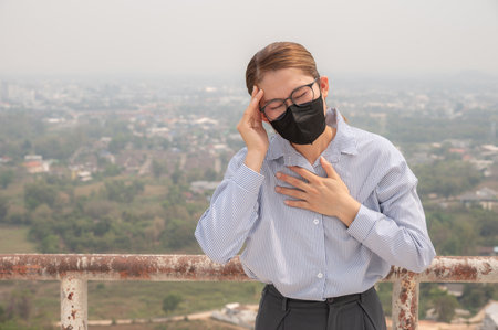 Asian woman having headache becaused of by Bad air pollution (PM2.5). PM2.5 levels meaning the air quality posed a health hazard.の写真素材
