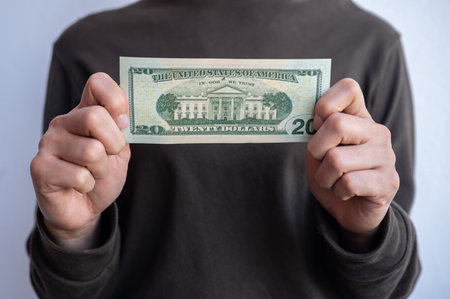 Cropped shot view of woman holding and showing twenty American dollar banknotes in hands.の写真素材