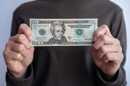 Cropped shot view of woman holding and showing twenty American dollar banknotes in hands. The US Dollar is the currency of United States.の写真素材