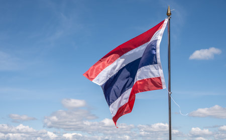 A Thailand national flag blowing by wind against blue sky. The flag of Thailand is a symbol of being a country.の写真素材