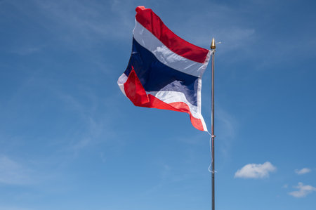 A Thailand national flag blowing by wind against blue sky.