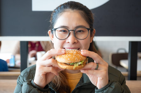 Portrait of young Asian woman holding a hamburger in hand before eating.の写真素材