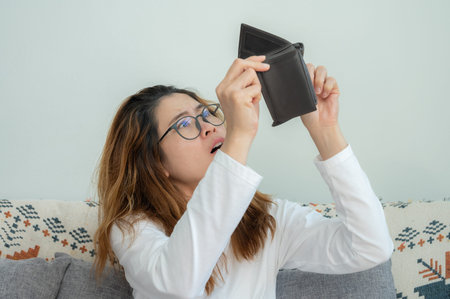 Asian woman trying to find money in her empty wallet. Having financial problems means being unable to pay debts over the short or long term.の写真素材