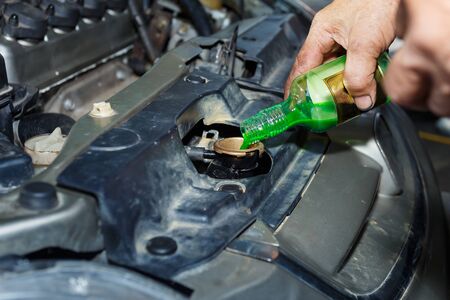 Oil change,Pouring oil to car engine, car mechanic changing motor oil in automobile engine at maintenance repair service station in a car workshop,Coolant.の写真素材