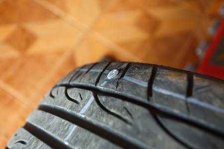 solve problem wheel in garage auto repair shop service. replacement repairman fixing car's tire trying to remove nail from hole. Flat tire. Accident with punctured tires concept.の写真素材