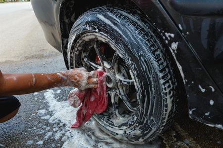 male hand is cleaning car tire, washing car.の写真素材