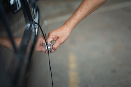 Black car Close up of human male hand opening car door, Background blur.の写真素材