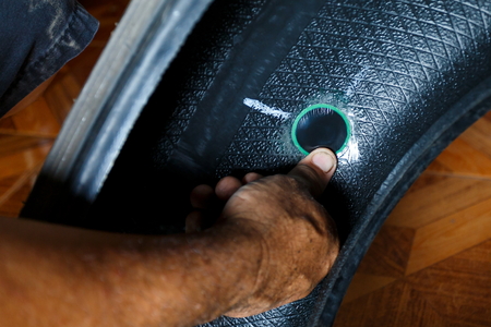solve problem wheel in garage auto repair shop service. replacement repairman fixing car's tire trying to remove nail from hole. Flat tire. Accident with punctured tires concept.の写真素材