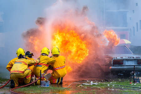 fireman using water and extinguisher car is on fire,Firefighter using extinguisher and water from hose for fire fighting,burning car Gas,Rescue Equipmen,Pixelation,Noise.の写真素材