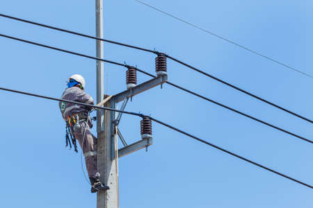 Electricians Wiring Cable repair services,worker in crane truck bucket fixes high voltage power transmission line,setting up the power line wire on electric power pole.の写真素材