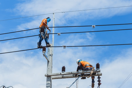 Electricians are working on the high voltage electric line in Thailand,Technician going up the pole...