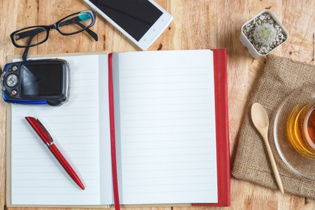 Notebook with pen, phone and cup of tea on wooden table,Aerial view (Design Mockup, poster) of a desk with an open notebook,diaryの写真素材