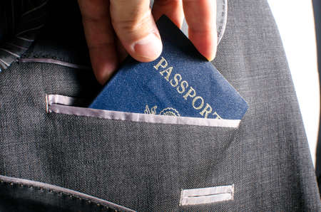A passport being placed into a suit pocket 