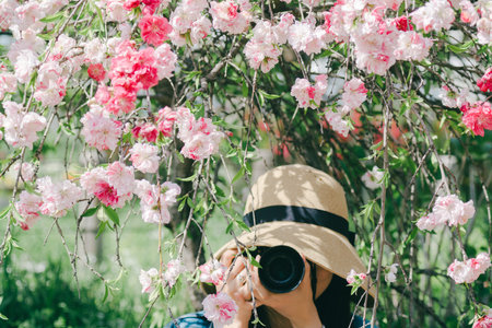 Girl in a hat with a camera on a background of flowering trees.の写真素材