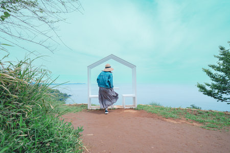 Asian woman standing in front of a pavilion at the sea.