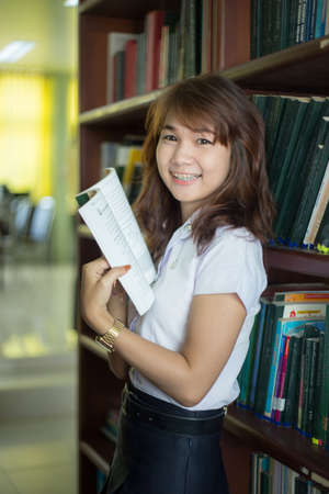 Pretty woman reading a book sitting on the floor in a book roomのeditorial素材