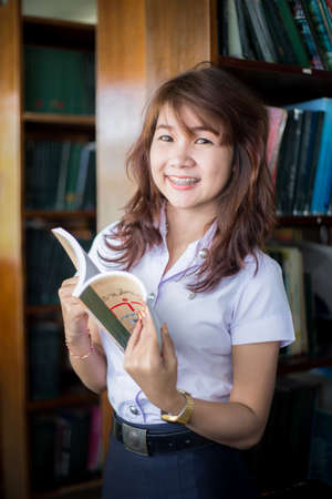 Pretty woman reading a book sitting on the floor in a book roomのeditorial素材