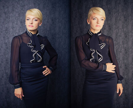 Blonde business woman in black suit staying in front of dark wallの写真素材