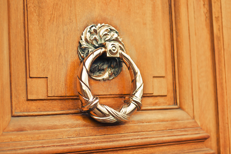 A brown door with beautiful golden retro style carved handle (knocker)の写真素材