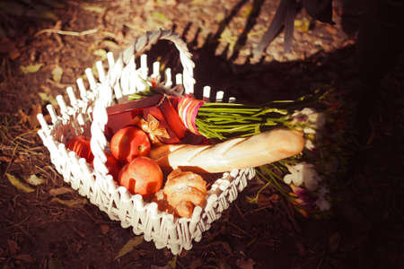Closeup french baguette, apples and flowers in the white basketの写真素材