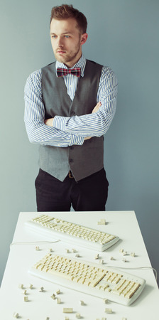 Young computer geek with beard in suit near the table with disassembled keyboardsの写真素材
