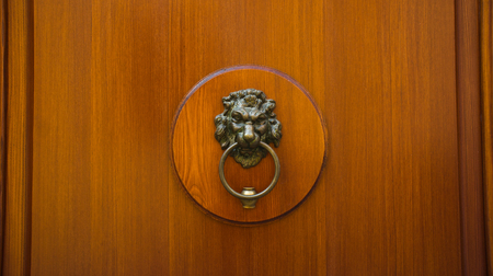 A brown door with ancient style carved lion head handle  knocker の写真素材
