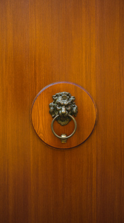 A brown door with ancient style carved lion head handle  knocker の写真素材