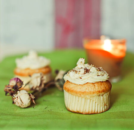 White cupcakes on the green towel with flowers and candlesの写真素材