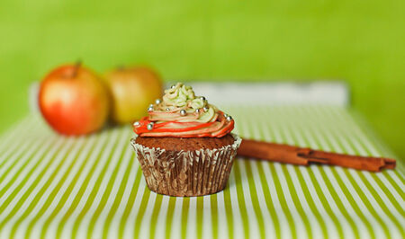 Coloured cupcake with an apples and stick of cinnamonの写真素材
