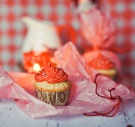 Red cream cupcakes with candies, candle and jugの写真素材