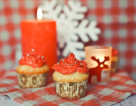 Red cream cupcakes with candies, snowflake, deer and candleの写真素材