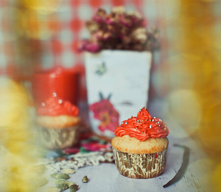 Red cream cupcakes with candies and candleの写真素材