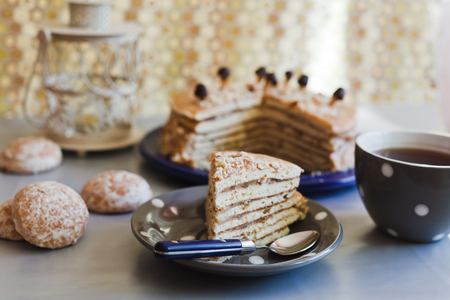 Closeup slice of a cake on a plate with tea in grey cupの写真素材