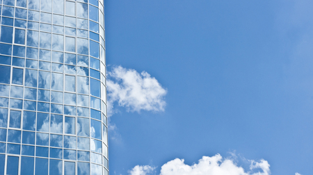 Reflection of clouds on the skyscraper made of glass and steelの写真素材