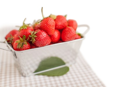 Metal box full of ripe strawberries with leafの写真素材