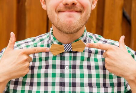 Portrait of nerd indicating at retro wooden bowtieの写真素材