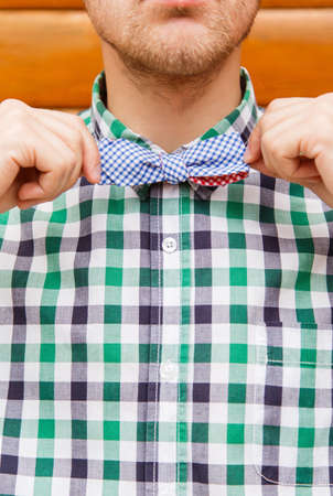 Fashion portrait of businessman correcting his bowtie on a wooden backgroundの写真素材