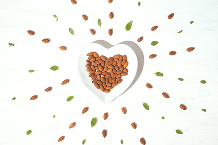 Heart shaped plate with almonds on the white backgroundの写真素材